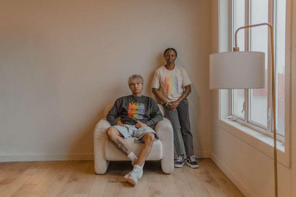 Two people sitting in a room with a large window and lamp.